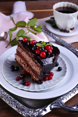 Delicious chocolate cake with berries and cup of coffee on table close up