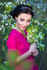 portrait of beautiful brunette woman in pink dress in blooming c