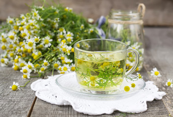 Chamomile tea in a glass cup on a wooden background