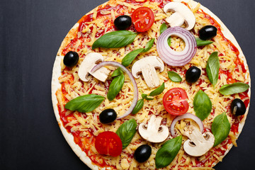 Raw pizza with vegetables on wooden background