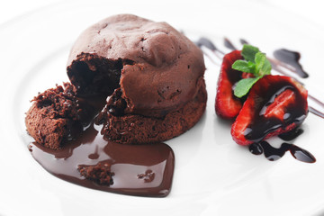 Chocolate fondant with strawberries on white plate, closeup