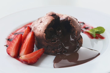 Chocolate fondant with strawberries on white plate, closeup