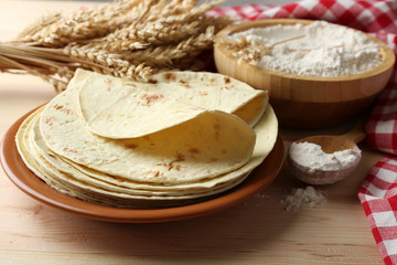 Stack of homemade tortilla on plate, on wooden table background