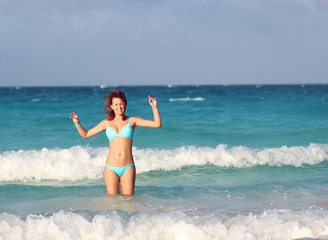 The redhead young woman standing in the ocean water