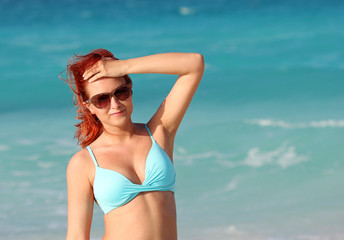 The redhead young woman standing in the ocean water