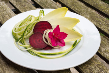 Aerial view Belgian endive, beetroot, zucchini salad on white plate