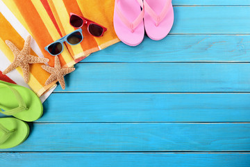 Beach background border scene with old blue wood deck decking sunglasses and sunbathing towel...