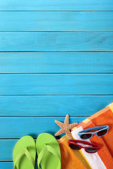 Beach background border with old blue wood deck decking sunglasses and sunbathing towel summer...
