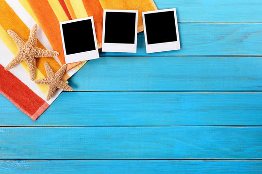Beach background border with three several polaroid style photo print frame on old blue wood deck decking and sunbathing towel summer holiday vacation album