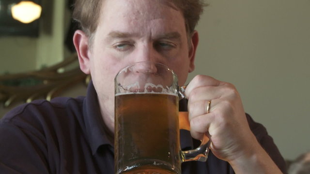 Close up of man drinking a glass of beer.