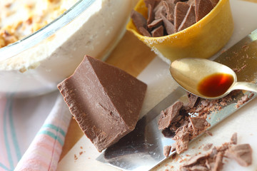 Block of chocolate, some chopped in measuring cup, with vanilla, and mixing bowl of batter