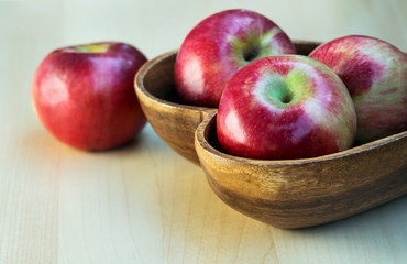 Apples in the wooden heart shape plate on the table, close up