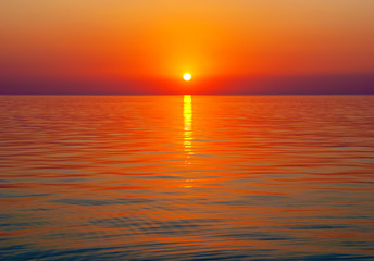 Bright sunset above tranquil sea surface with golden sun path