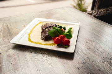 Grilled beef steak and mushrooms with tomatoes on wood table