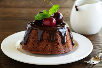Chocolate cake with icing and a cherry.