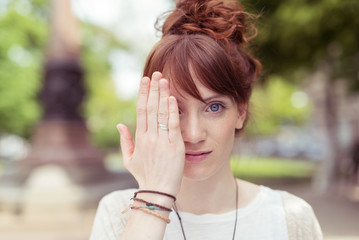 junge frau versteckt ein auge hinter ihrer hand