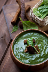 Close-up of spinach cream-soup in a wooden bowl, studio shot