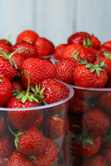 Fresh strawberries in a plastic bowl on wooden background