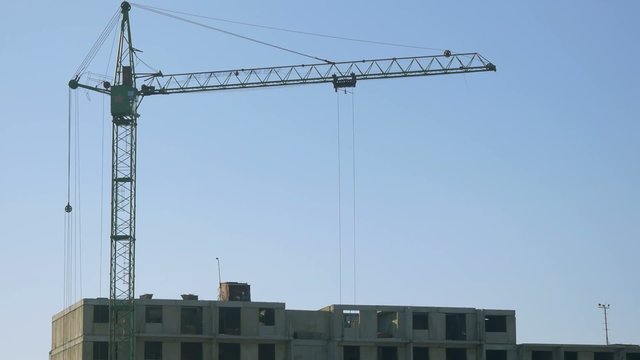 Crane on the construction site with workers by winter