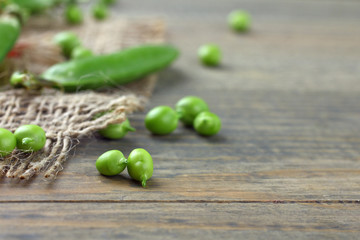 Fresh green peas on a wooden background. Peas on sacking