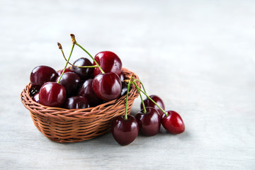 Fresh cherry berries in bark basket on wooden background