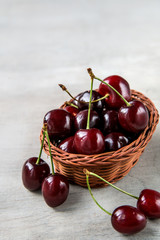 Fresh cherry berries in bark basket on wooden background