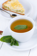 Mint tea with slice of rhubarb pie on wooden table.
