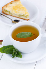 Mint tea with slice of rhubarb pie on wooden table.