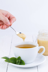 Mint tea with honey on wooden table.