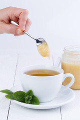 Mint tea with honey on wooden table.