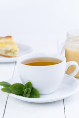 Mint tea with honey on wooden table.