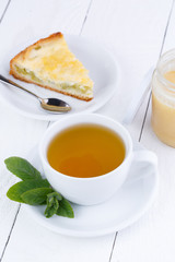 Mint tea with slice of rhubarb pie on wooden table.