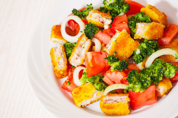 Fresh vegetable salad with fried breaded fish fillets