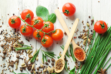 Tomatoes with wooden spoons with fresh herbs and spices on wooden background