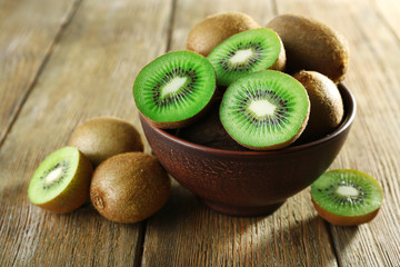Juicy kiwi fruit in bowl on wooden background