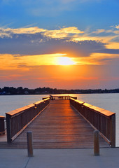 Man fishing on pier at sunset