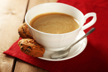 Cup of coffee with cookie on table, closeup