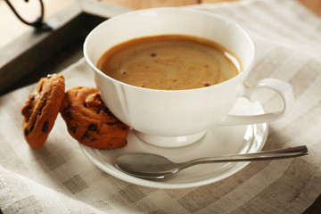 Cup of coffee with cookie on table, closeup