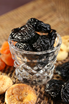 Prunes and other dried fruits on wicker mat, closeup