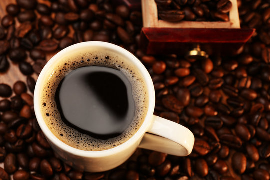 Cup of fresh coffee with beans on table, closeup © Africa Studio