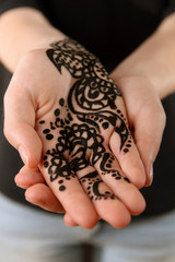 Closeup image of henna on female hand on dark background
