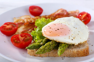 Dish of asparagus and egg in plate on table, closeup