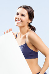 Woman in fitnesswear showing signboard, over grey