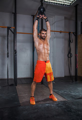 Muscular man exercise with kettle-bell in cross club.