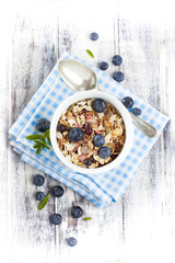 Fototapeta na wymiar Bowl of muesli with fresh blueberries on white wooden table