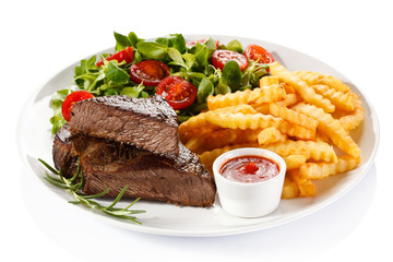 Grilled steak, French fries and vegetables on white background 