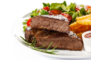 Grilled steak, French fries and vegetables on white background 