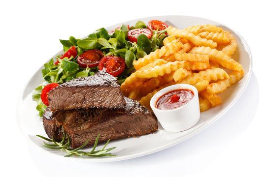 Grilled steak, French fries and vegetables on white background 