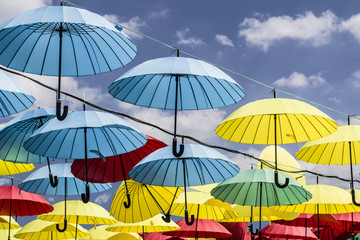 colored umbrellas hanging from a rope sky background
