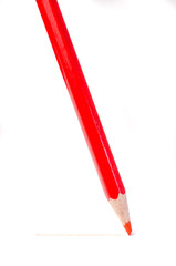 Sharpened red pencil draws a line on a white paper